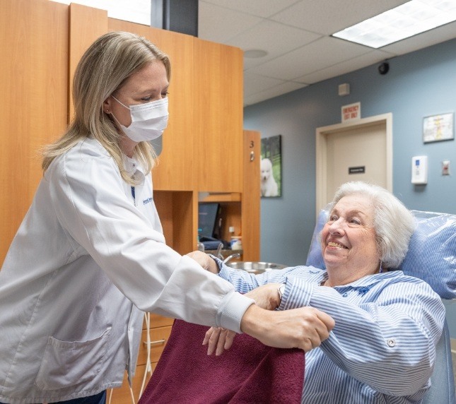 Dentist putting blanket over senior female patient