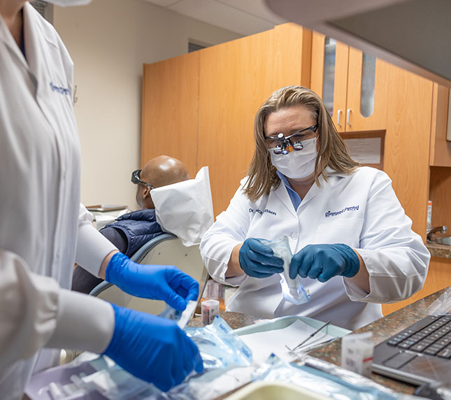 Dentist working with instruments with patient in background