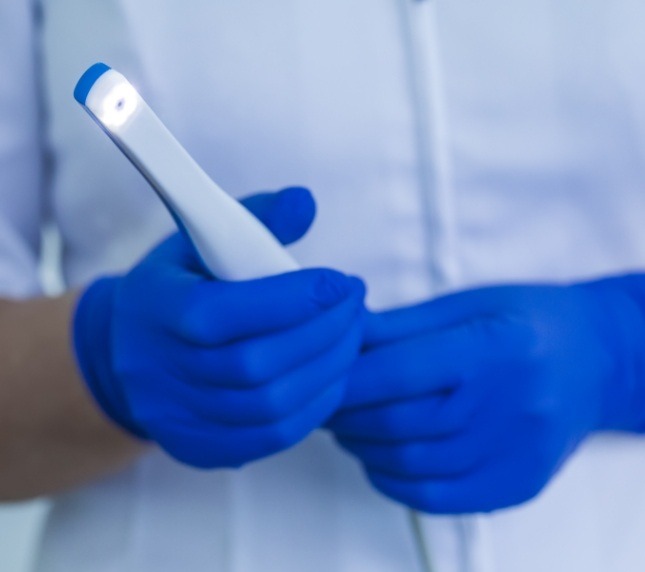 Gloved hands holding an intraoral camera