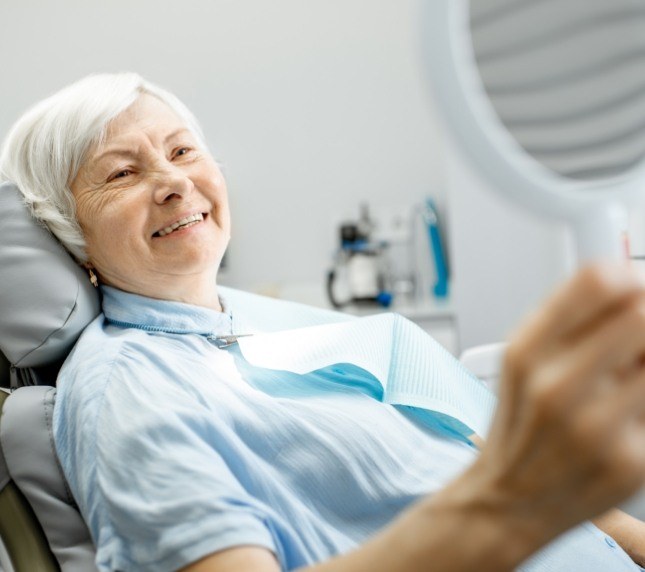 Senior woman leaning back in dental chair and smiling