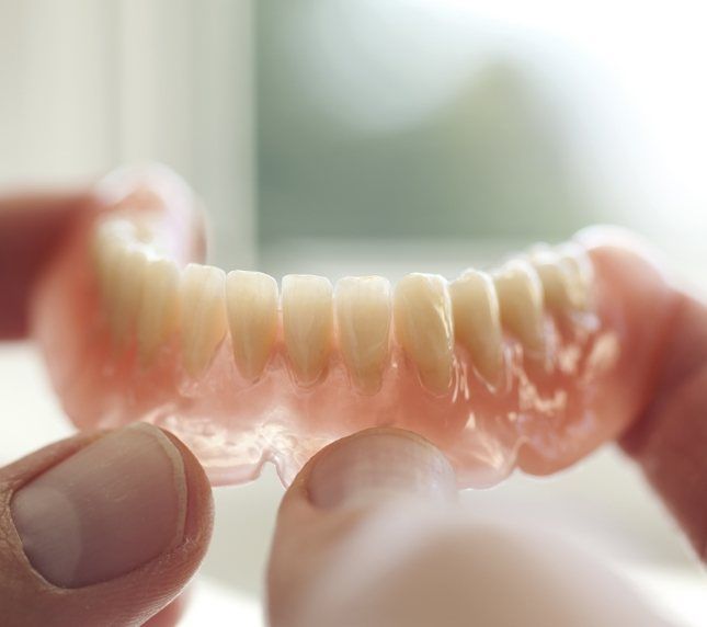 Close up of hands holding dentures for lower arch