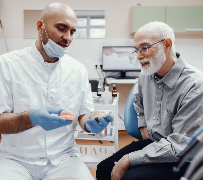 Dentist showing senior patient dentures