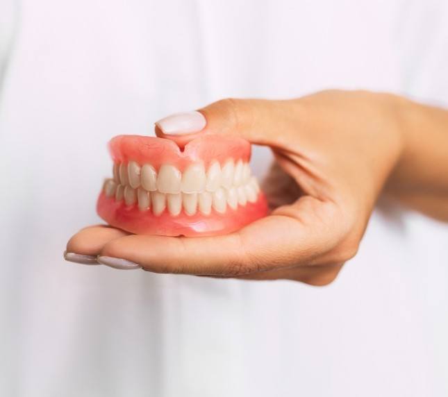 Close up of hand holding full dentures