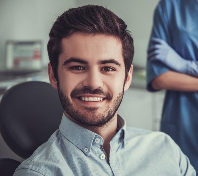 Male patient sitting in dental chair and smiling