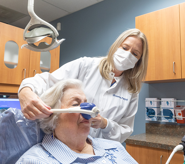 Placing mask over patients nose for sedation dentistry in Owings Mills