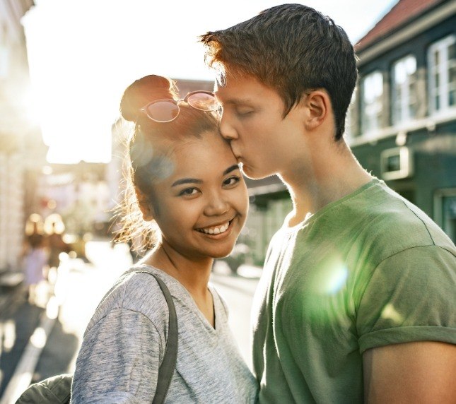 Man kissing woman on forehead in middle of street